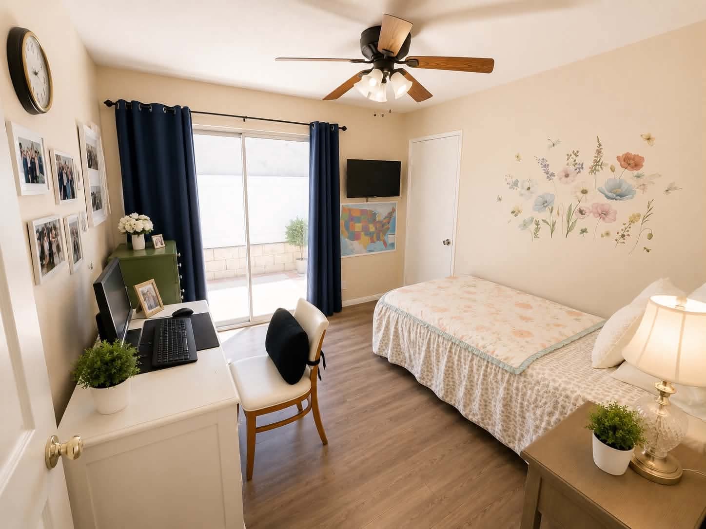 A bright single bedroom at Tessa Place 2 with floral wall art and a desk.