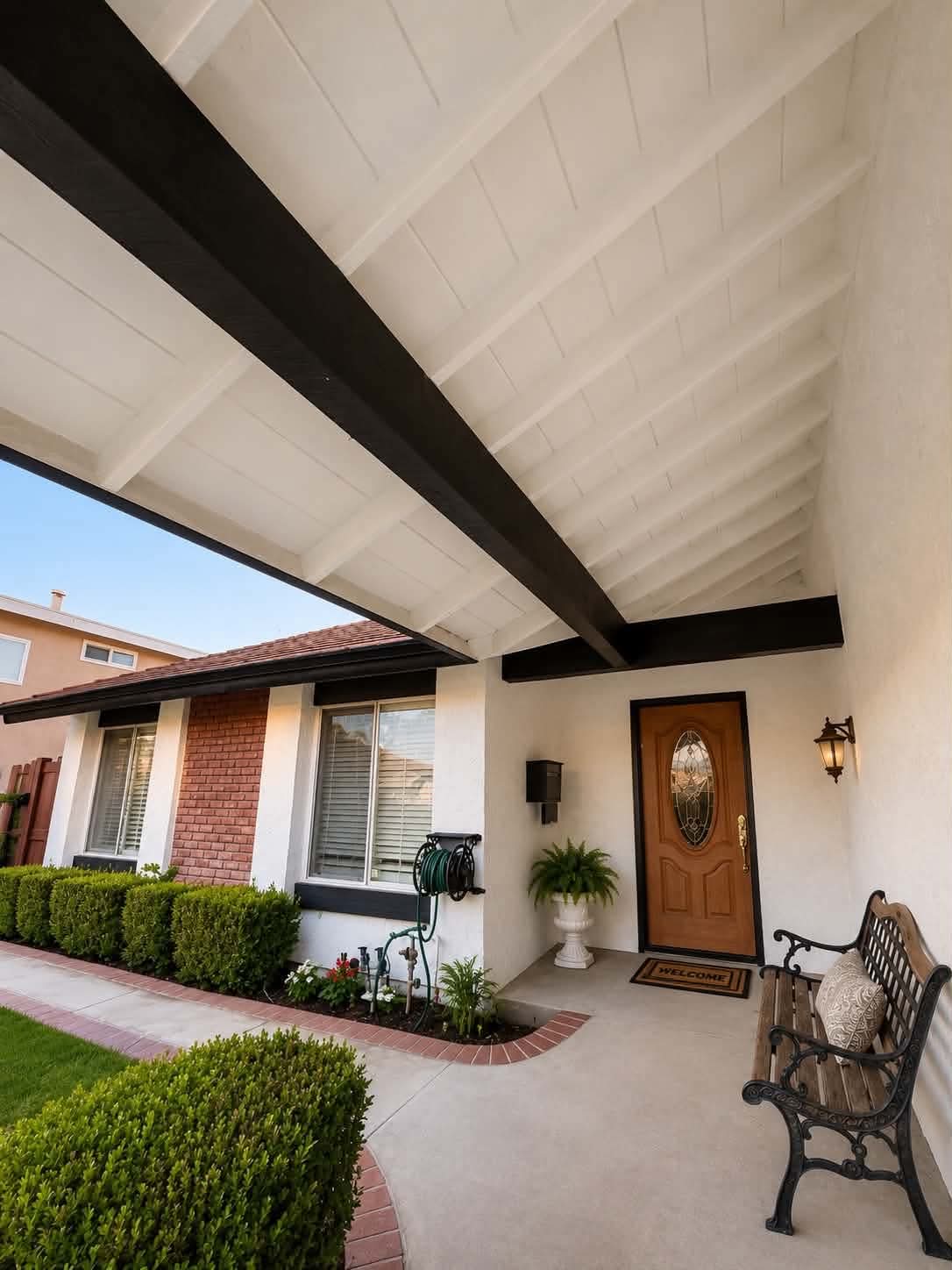 The covered front entry of Tessa Place 2 with a welcoming bench and warm wood door.